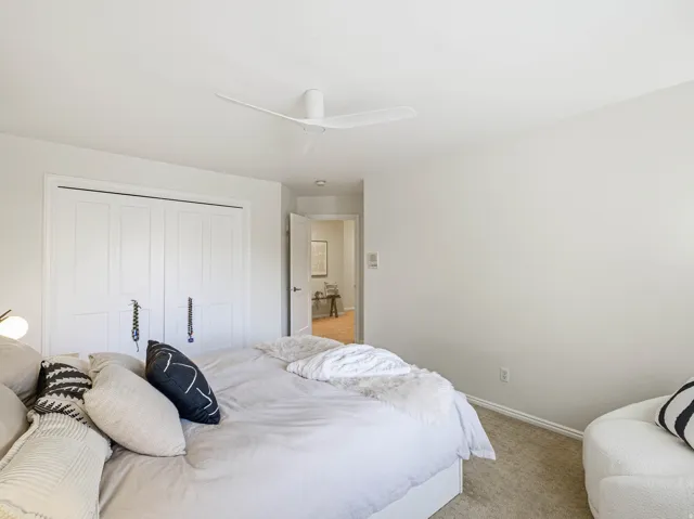 Bedroom featuring neutral-toned carpeting and a white ceiling fan