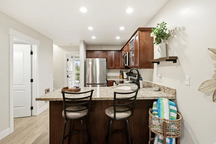 Kitchen featuring wood-finish cabinetry, stainless steel appliances, speckled stone countertops, and recessed lighting
