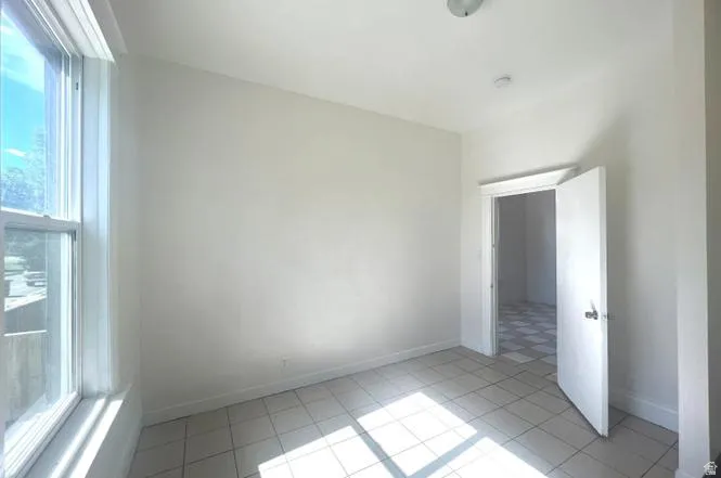Room featuring a large window, light-toned wall paint, recessed ceiling lighting, and a white tiled floor