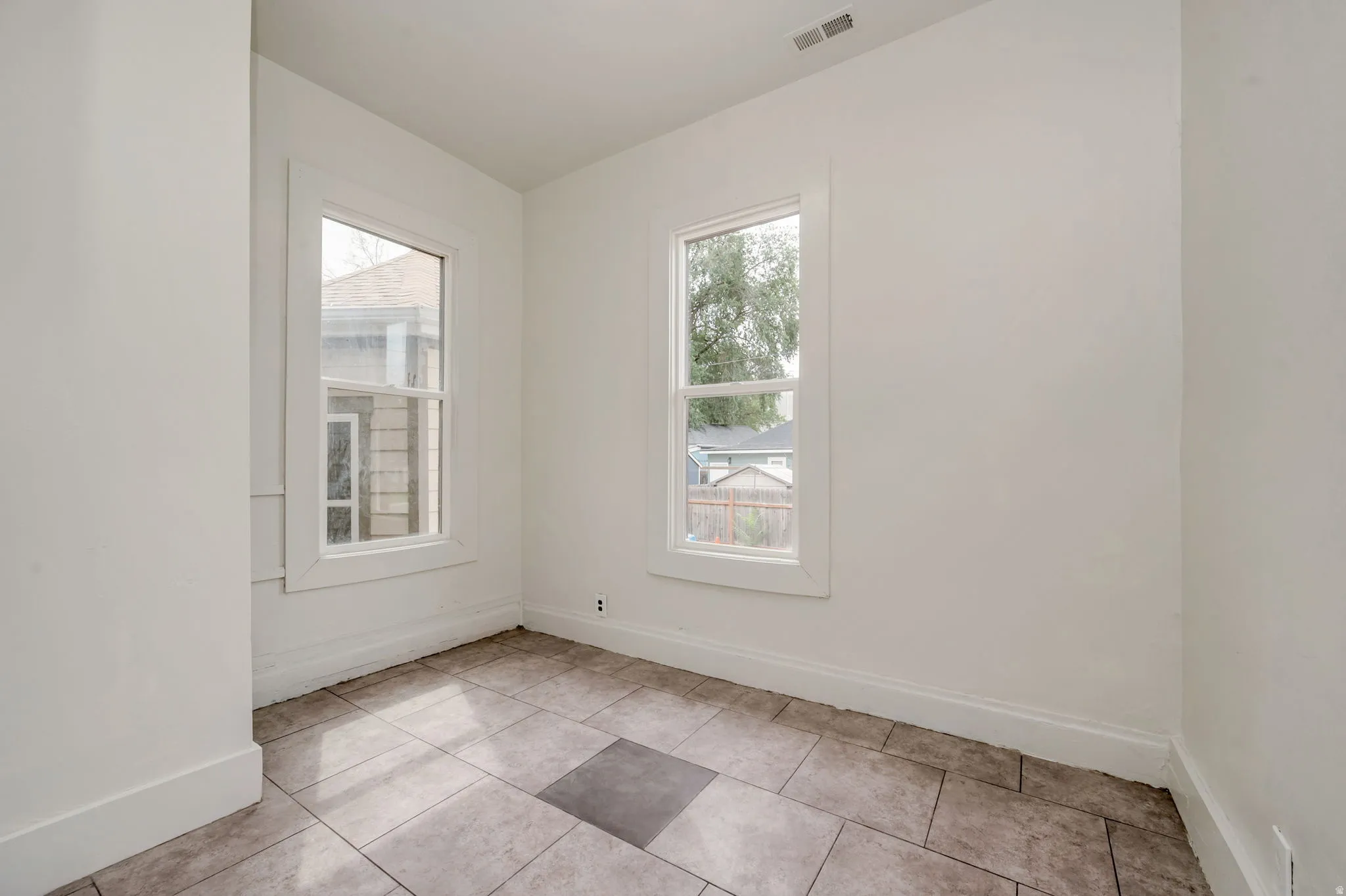 Bright room with two double-hung windows, featuring white trim and baseboards