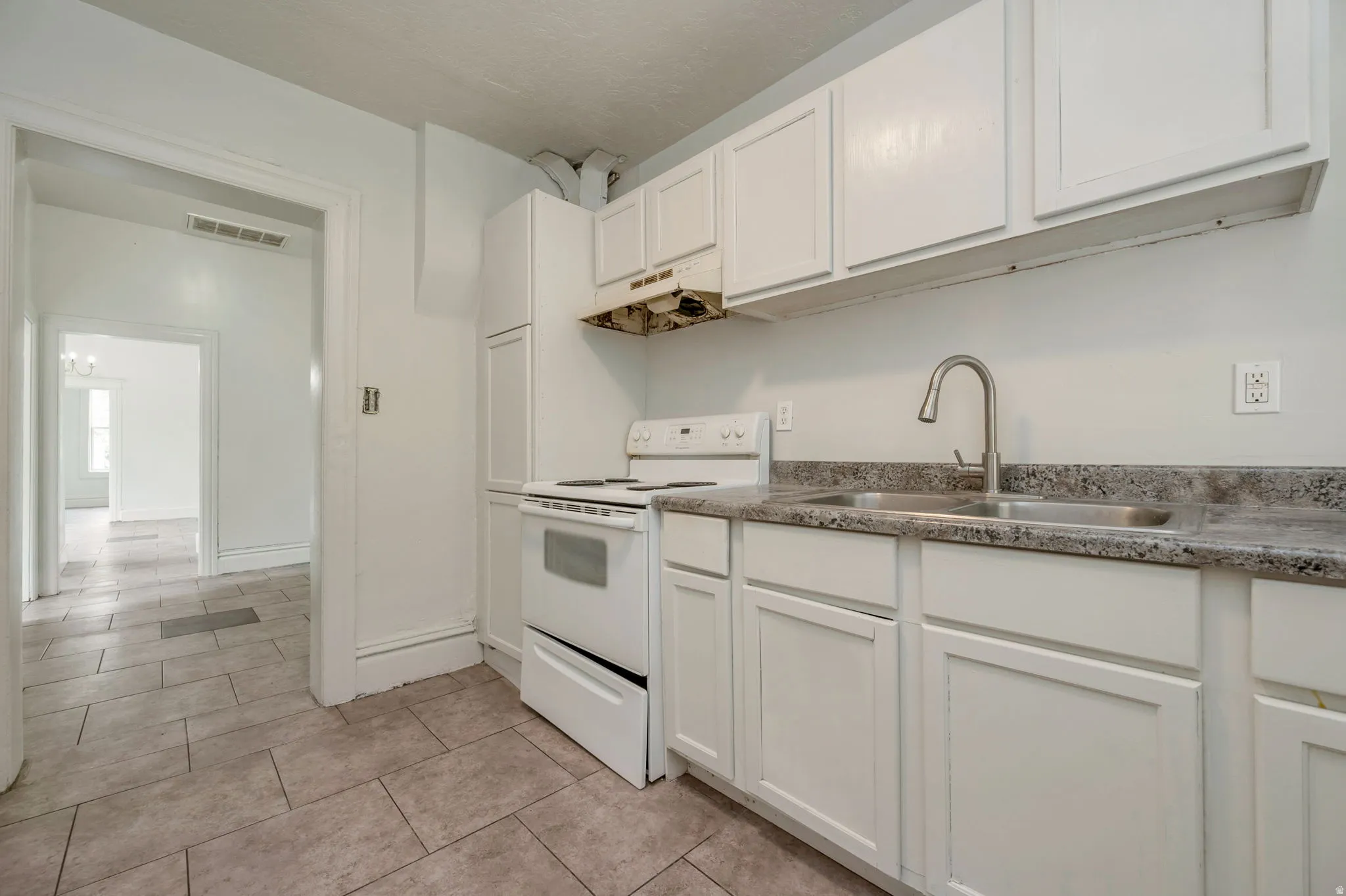Kitchen featuring white cabinetry, a double basin stainless steel sink with a gooseneck faucet, a white range, and a tile floor