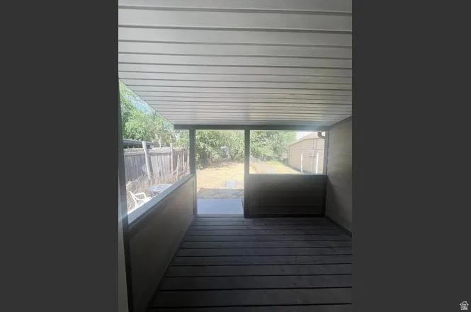 Covered outdoor patio featuring wood-finish flooring, a solid privacy wall, and a view of the backyard