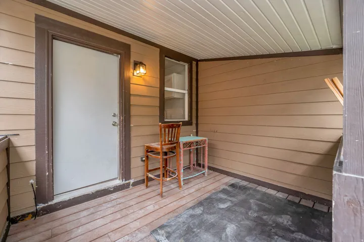 Covered exterior porch featuring tan horizontal siding and wood-finish flooring