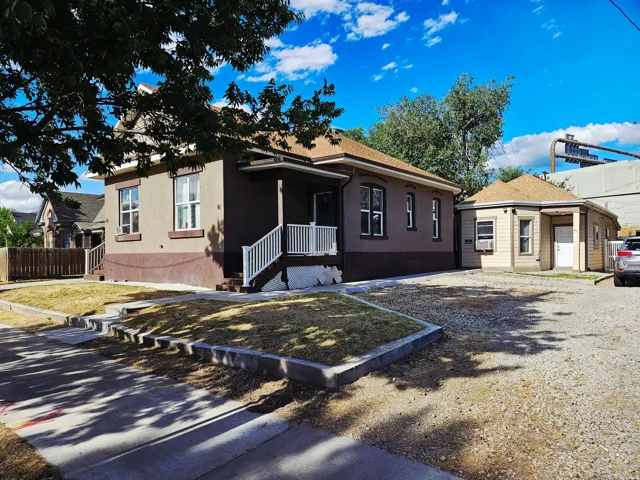 Two-story residence featuring a covered front porch with white railings, a two-tone exterior, and a secondary structure with a gabled roof