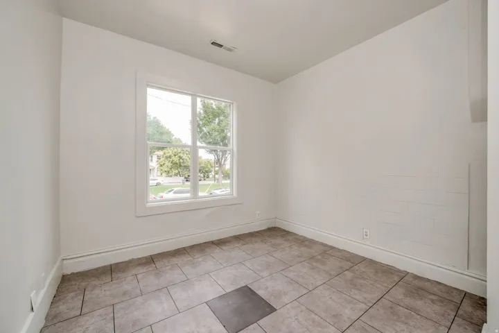 Room with a double-hung window, light-toned walls, and rectangular floor tiles