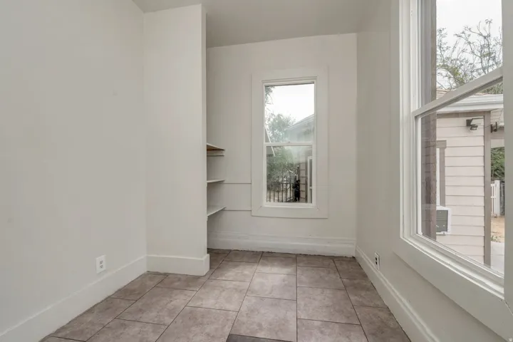 Interior space featuring tile flooring, white walls, and built-in shelving