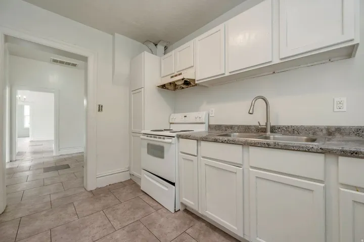 Kitchen featuring white cabinetry, a double basin stainless steel sink with a gooseneck faucet, a white range, and a tile floor