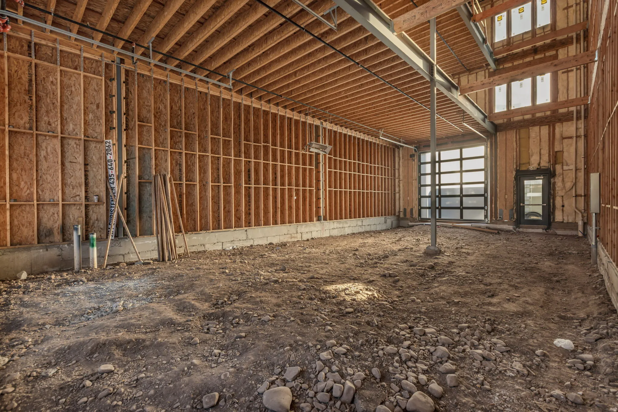 Unfinished interior space with exposed wood framing, concrete block foundation, and structural steel beams