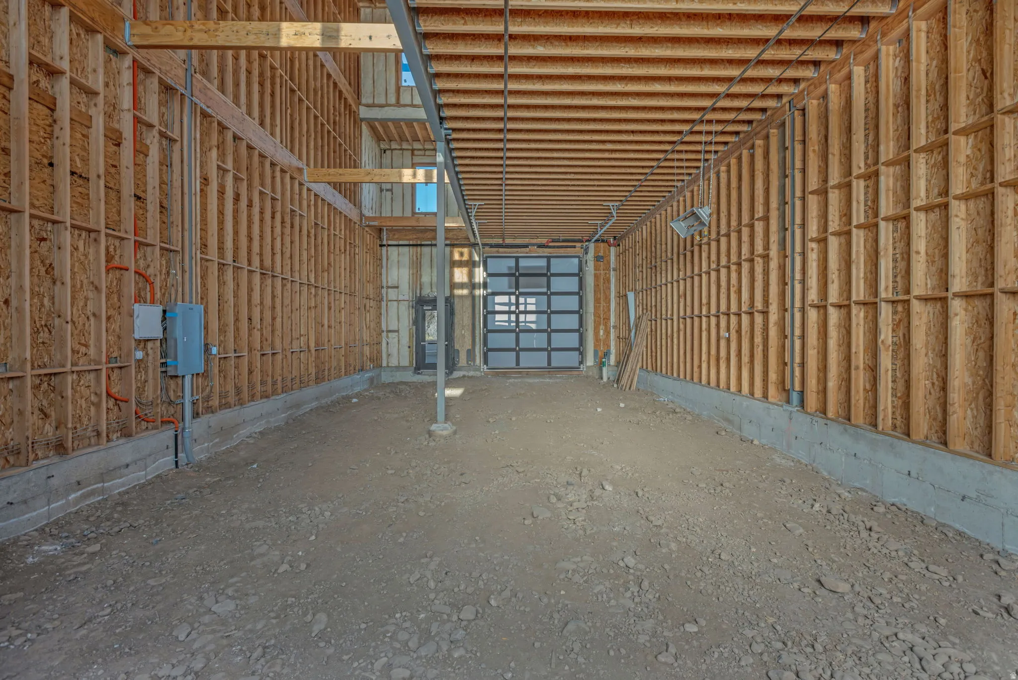 Unfinished interior space featuring exposed wood framing, concrete foundation, and a translucent panel garage door