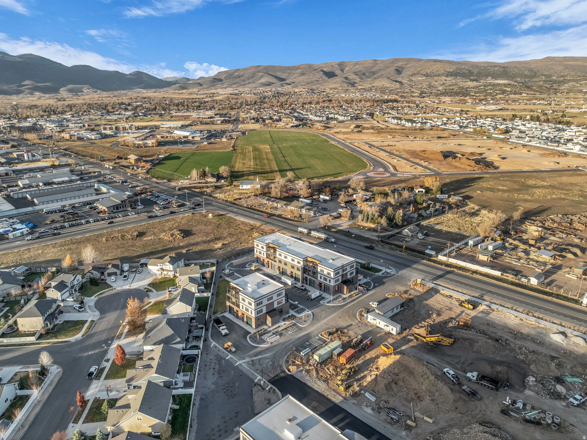Aerial perspective showcasing a developing community with residential structures, commercial buildings, and extensive land