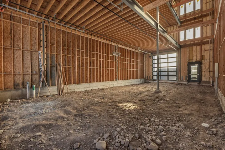 Unfinished interior space with exposed wood framing, concrete block foundation, and structural steel beams