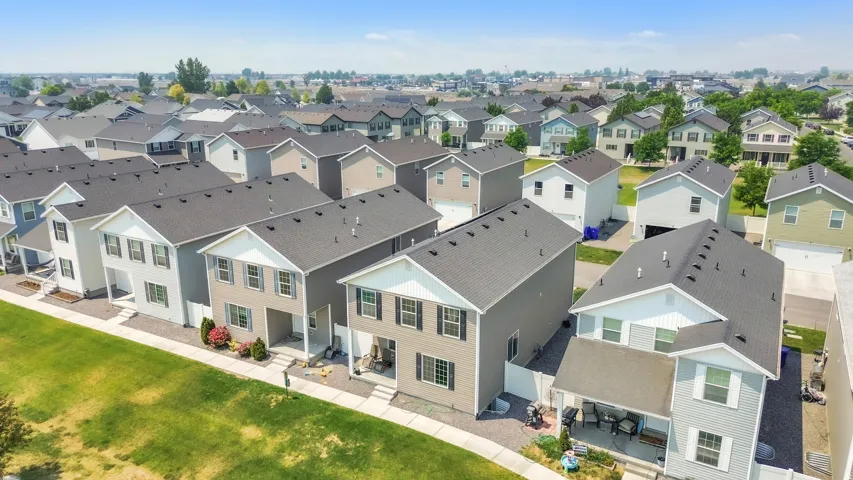 Residential street featuring multiple two-story homes with dark shingled roofs and light-colored siding