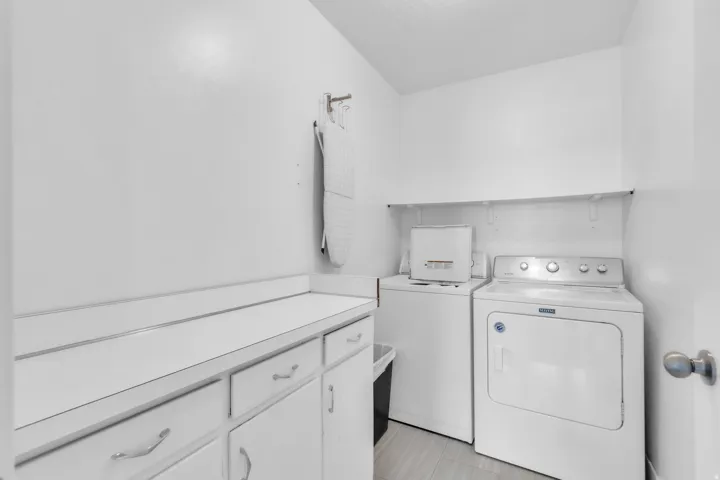 Dedicated laundry space featuring light-toned flooring and white walls