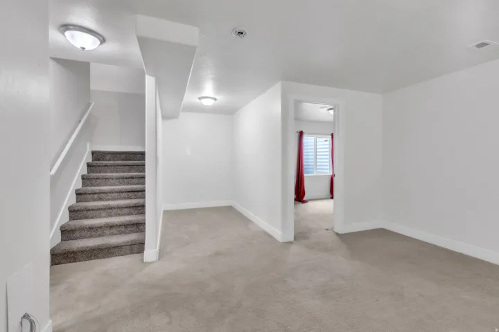 Carpeted living space featuring recessed lighting and a doorway opening to an additional room with a window