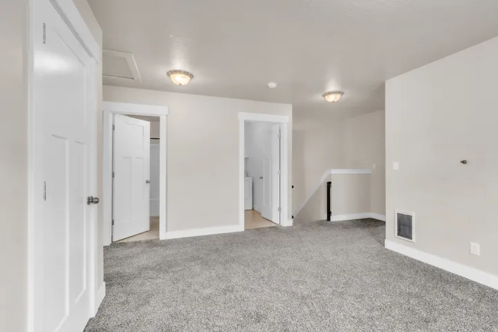 Spacious room featuring light gray carpeting, neutral wall paint, and white trim