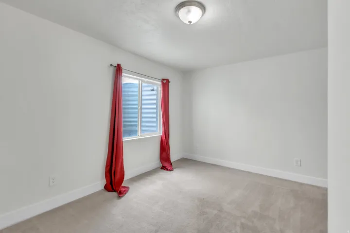Interior room featuring light gray carpeting, white walls, and a single window with white trim