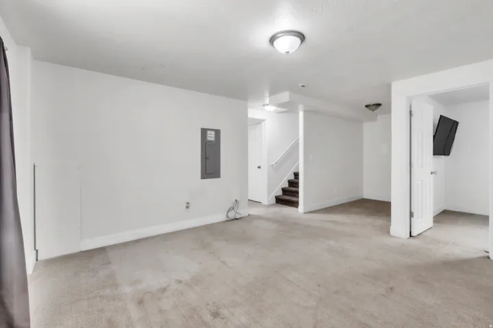 Carpeted room with white walls, recessed lighting, and a staircase