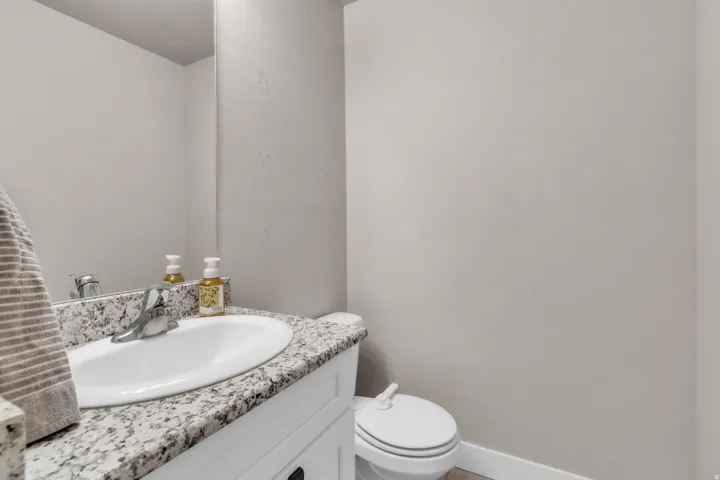 Bathroom featuring a vanity with a white rectangular sink, a speckled countertop, and a chrome faucet