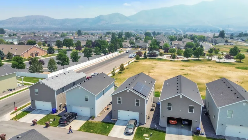 Residential street featuring multiple properties with attached garages, paved driveways, and landscaped front yards