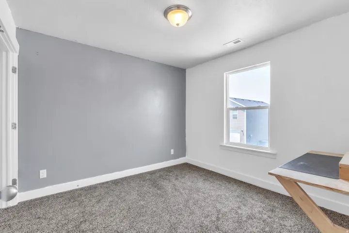 Carpeted room with a single window, white trim, and a semi-flush mount ceiling light fixture