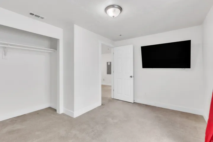 Carpeted interior space with a built-in closet featuring shelving and hanging rods
