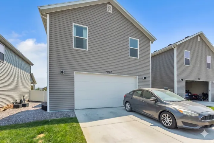 Two-story residential structure featuring gray horizontal siding and a white garage door