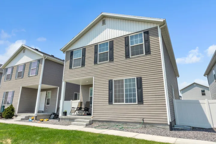 Two-story residence featuring light brown horizontal siding with white trim and dark window shutters