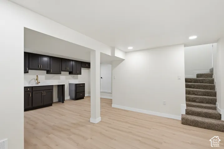 Finished lower level featuring light wood-finish flooring and recessed lighting