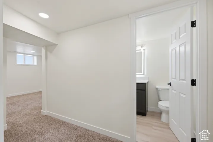 Contemporary bathroom featuring a dark wood-finish vanity with a white countertop, modern illuminated mirror, and light wood-finish flooring