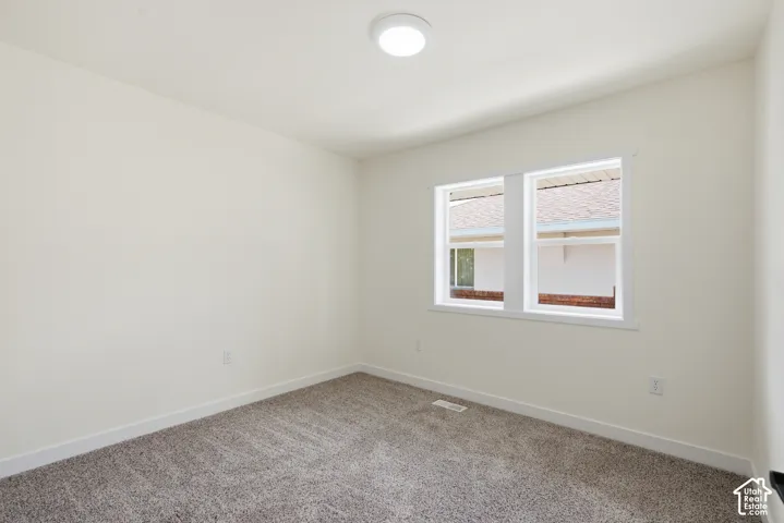 Bright room featuring a flush-mount ceiling light, dual windows with white trim, white wall finishes, and grey carpet flooring