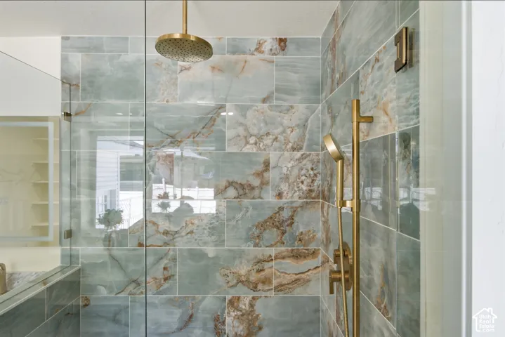 Shower enclosure featuring full-height glass panels and blue-green marbled tile with brown accents