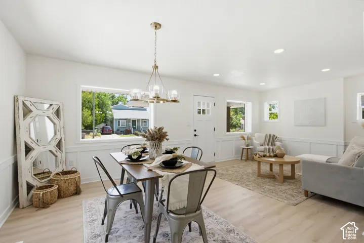 Open concept living and dining area featuring light wood-finish flooring, recessed lighting, white wainscoting, and large windows