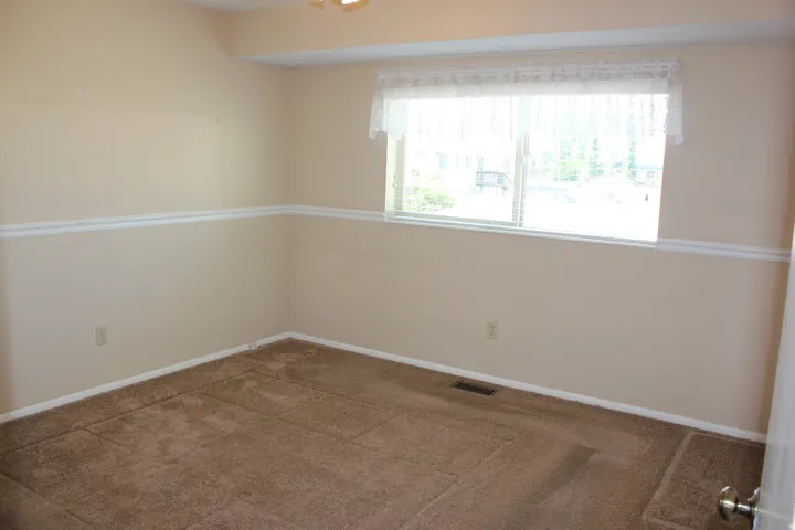 Neutral-toned walls with chair rail molding and carpeted flooring