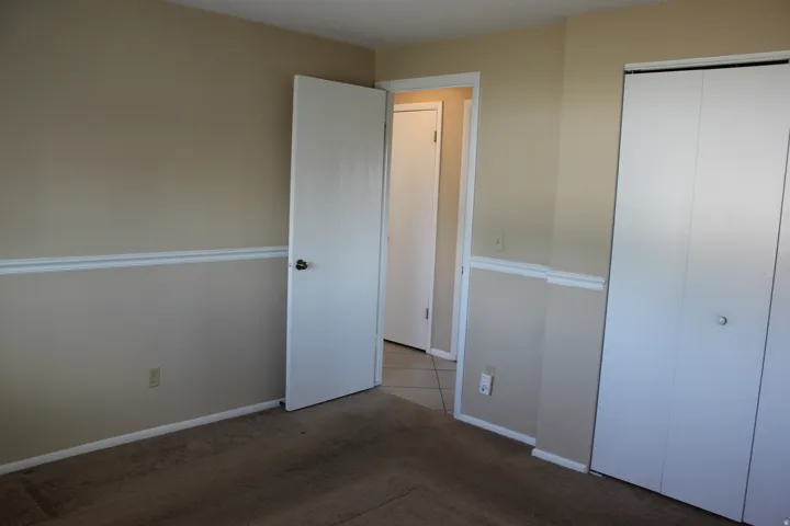 Wall trim detailing, neutral wall color, carpeted flooring, and white bifold closet doors