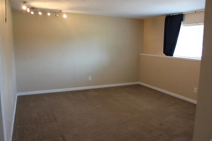 Spacious room featuring neutral wall finishes, carpeted flooring, recessed lighting, and a large window with natural light
