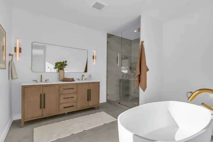 Dual vanity with light wood-finish cabinetry, white countertop, and gold-finish hardware