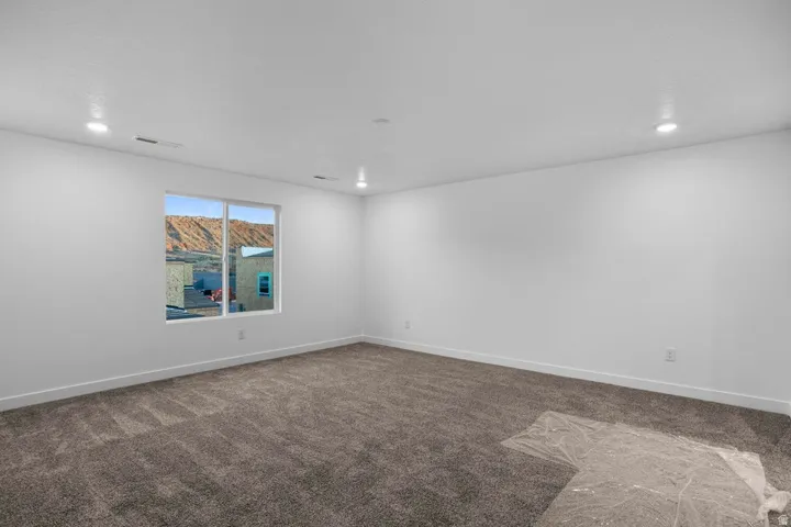 Spacious room featuring new carpeting, recessed lighting, base molding, a large picture window, and neutral white walls