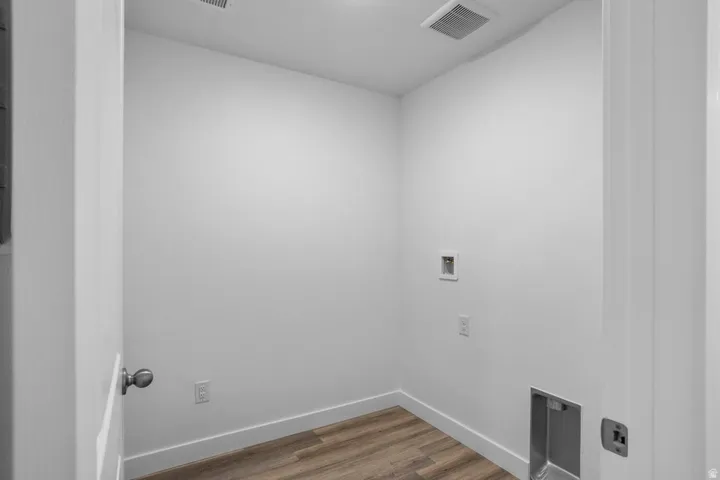 Dedicated utility space featuring wood-finish flooring, white baseboards, and a ceiling vent