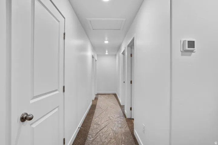 Hallway featuring recessed lighting, white walls, and neutral-toned carpeting