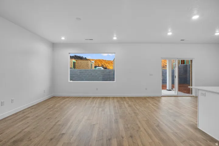 Spacious interior featuring wood-finish flooring, white walls, recessed lighting, and a large window
