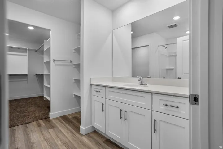 Bathroom vanity featuring a single sink, light-toned countertop, and white shaker-style cabinetry with chrome hardware