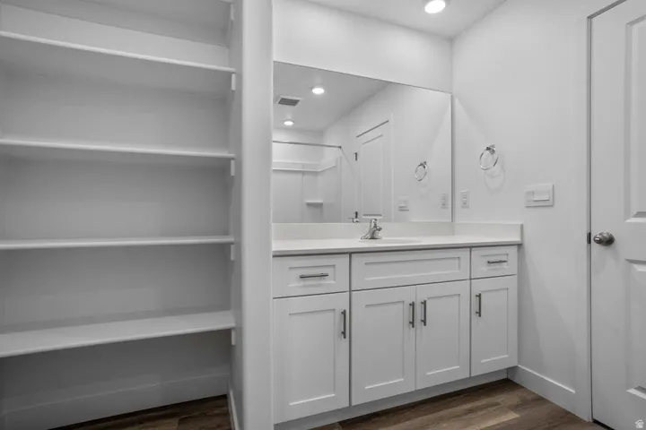 Bathroom vanity featuring white shaker cabinetry, an integrated sink, and a large mirror