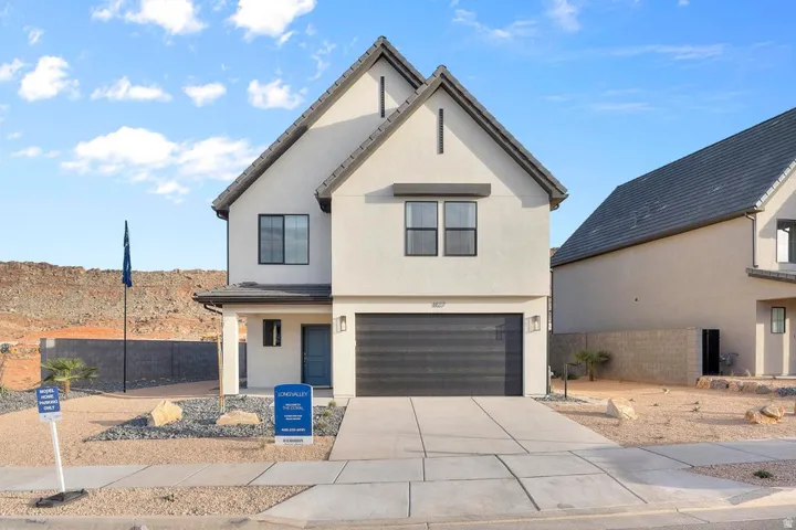 Modern two-story stucco exterior with a dark gray garage door