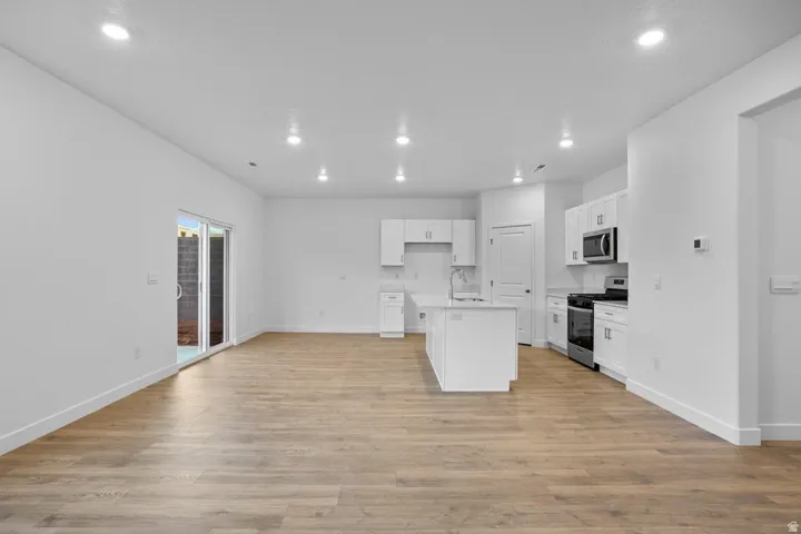 Open-concept living area featuring wood-finish flooring, recessed lighting, and a sliding glass door