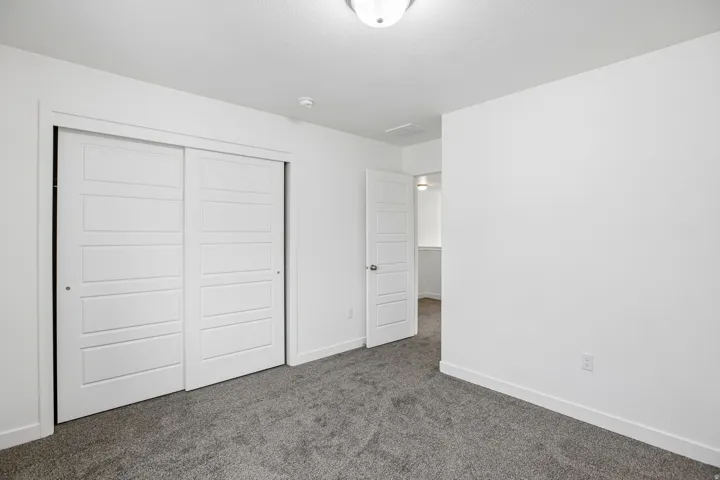Bedroom featuring sliding closet doors with horizontal paneling, gray carpet flooring, white walls, and a semi-flush ceiling light fixture