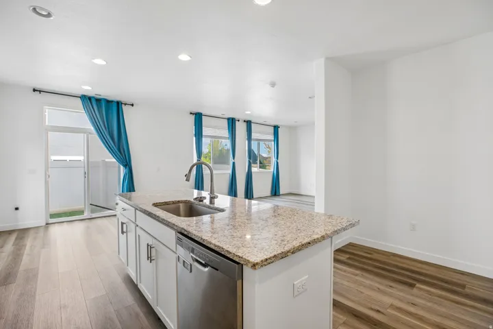 Kitchen island with granite countertop, integrated stainless steel sink, and stainless steel dishwasher