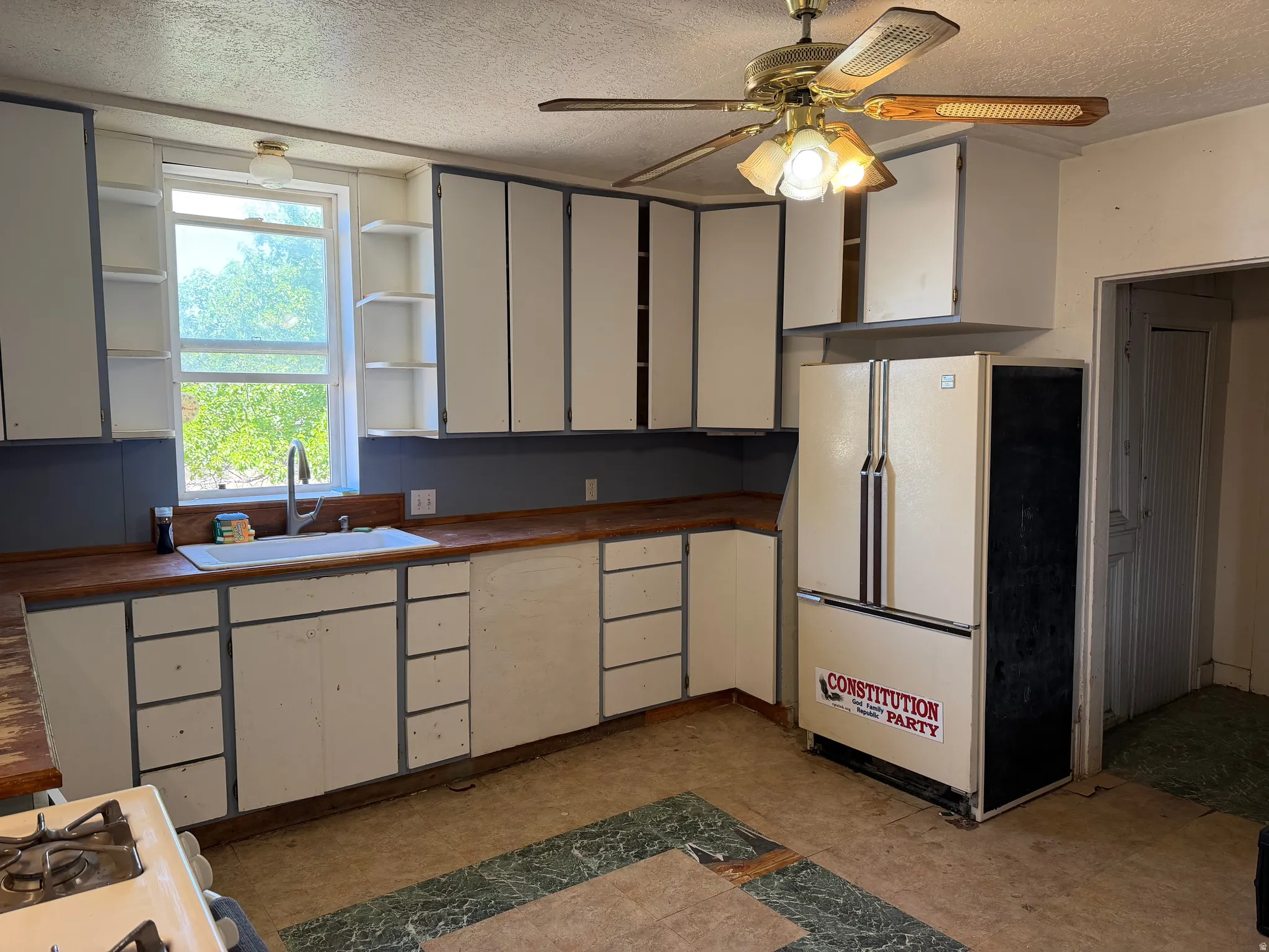 Kitchen featuring wood-finish countertops, white cabinetry with open shelving, and a dual-basin sink with a gooseneck faucet