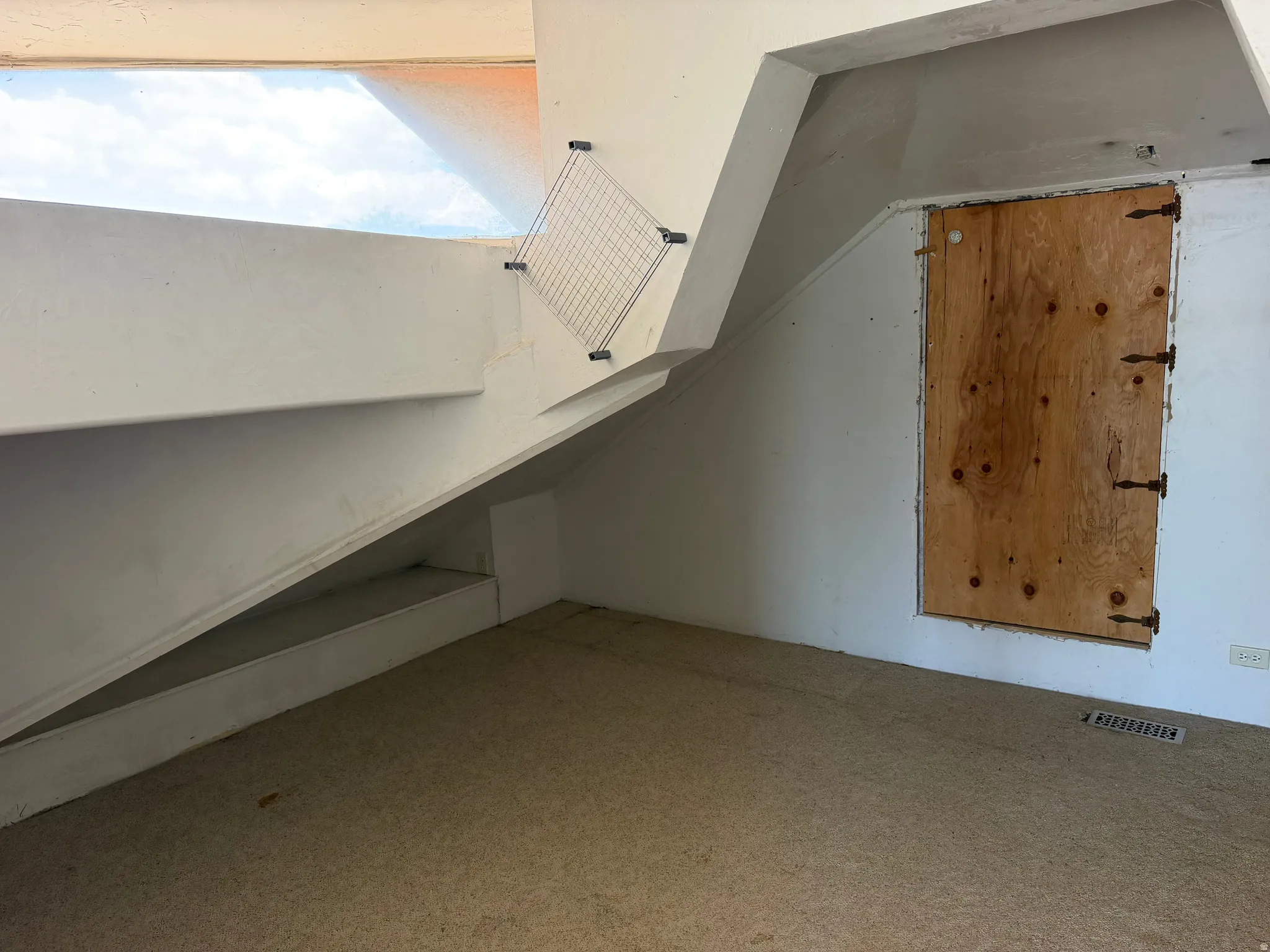 Carpeted floor with white walls and a light-filled upper window