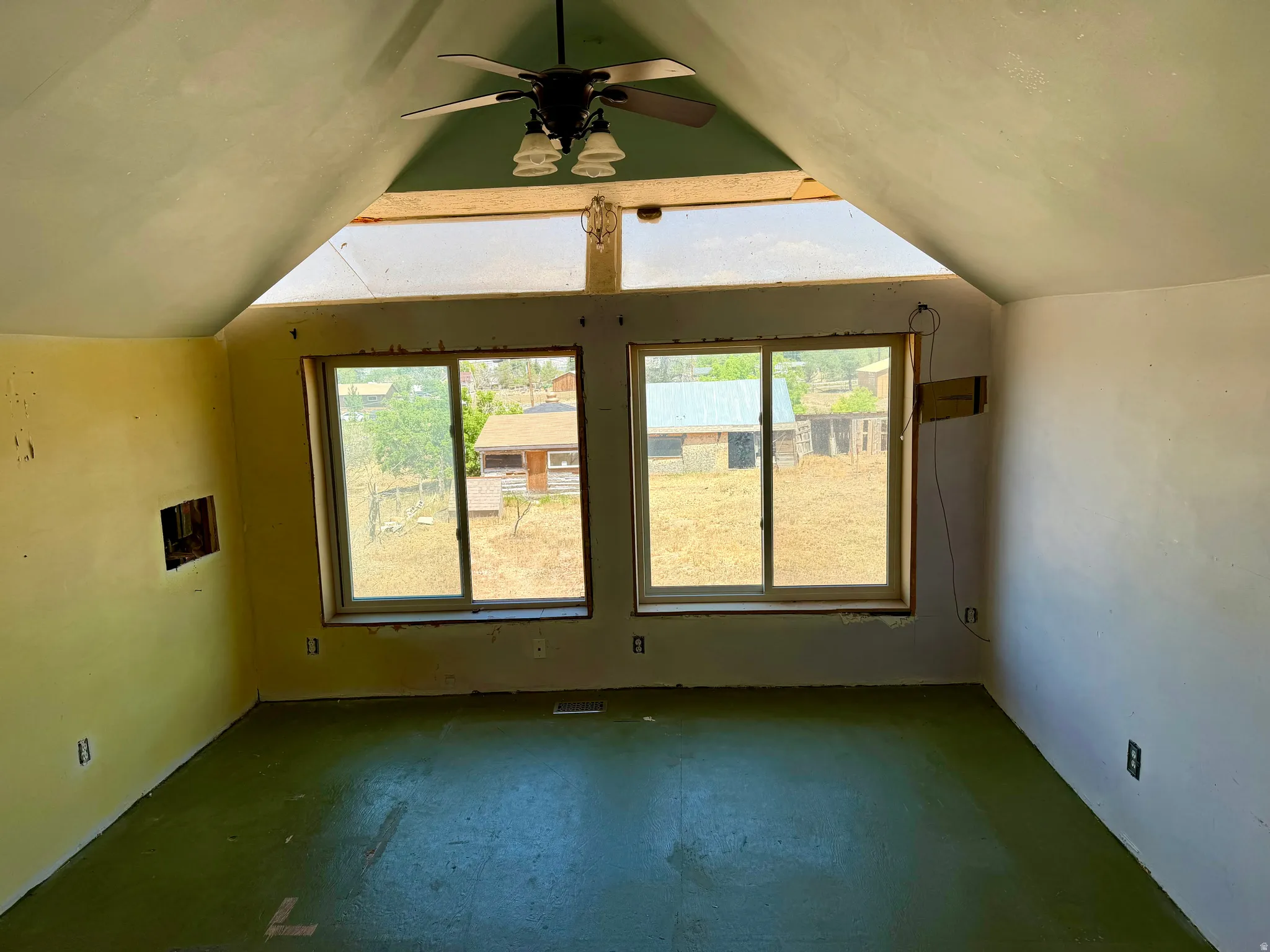 Spacious interior room with sloped ceilings and a ceiling fan
