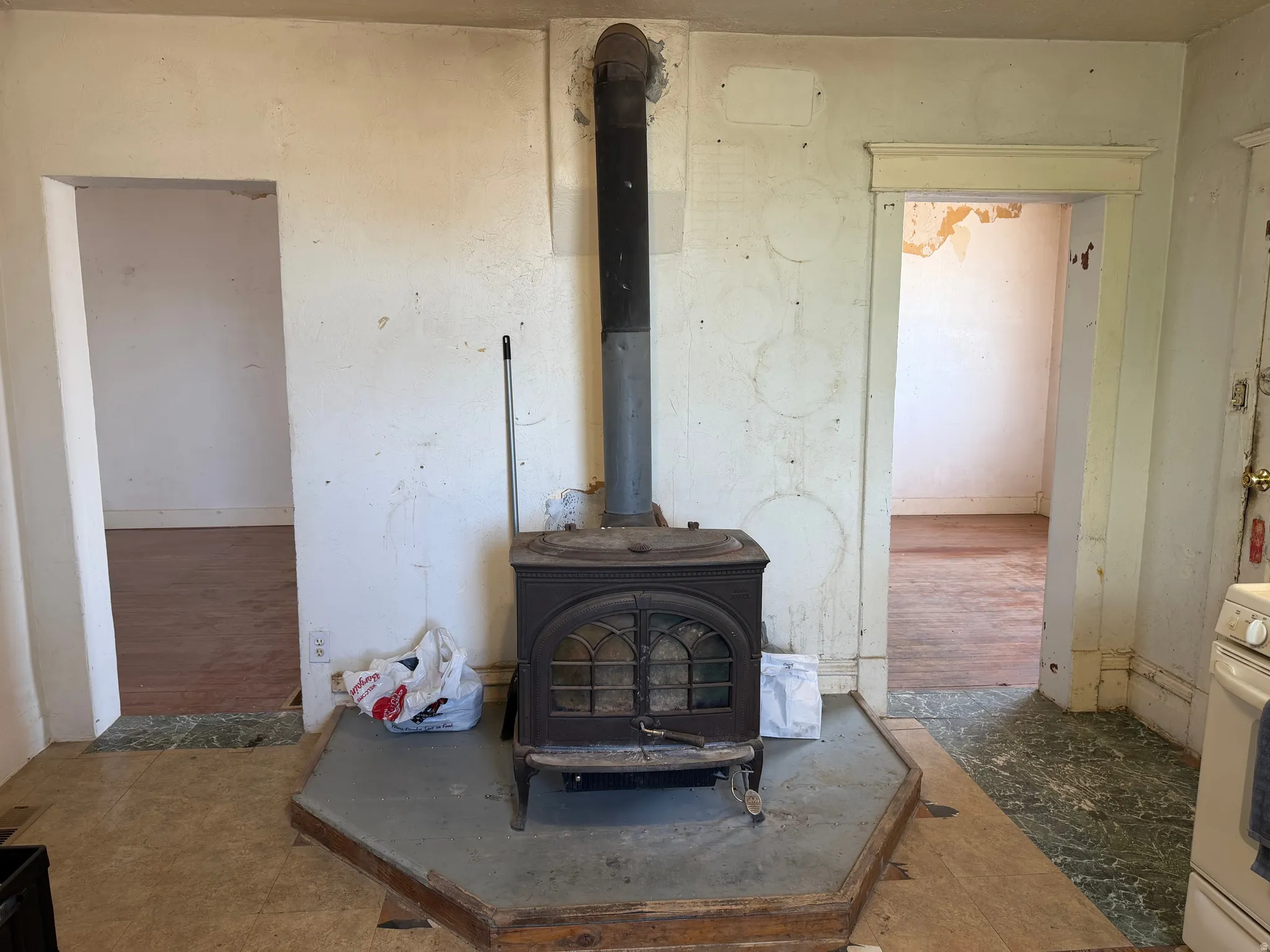 Cast iron wood-burning stove with a metal flue centered on a stone hearth